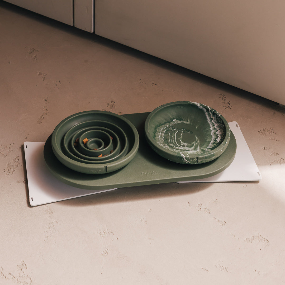Green PINO plateau with a spiral slow feeder bowl and a marbled water bowl on a white steel base plate