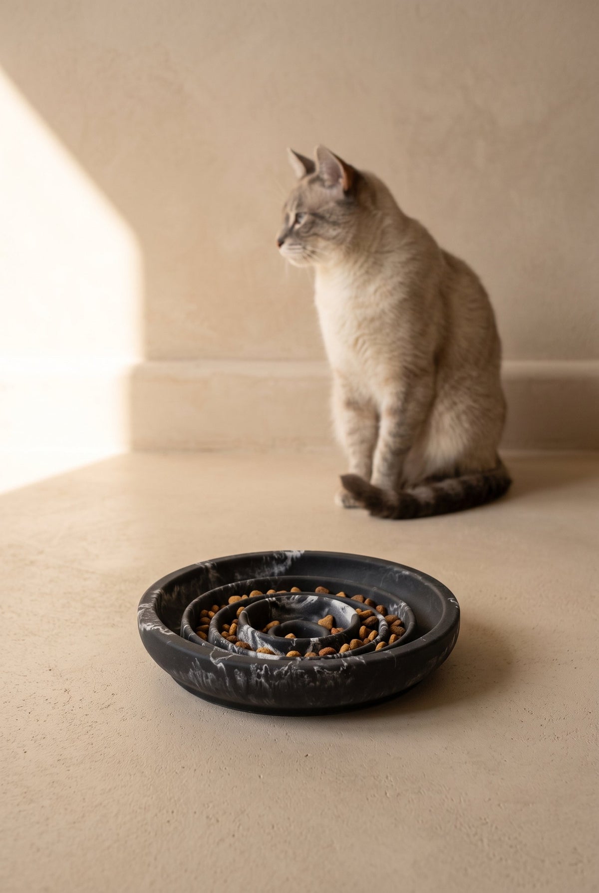 A cat sitting behind a marbled Black Panther Flat Slow Feeder Bowl